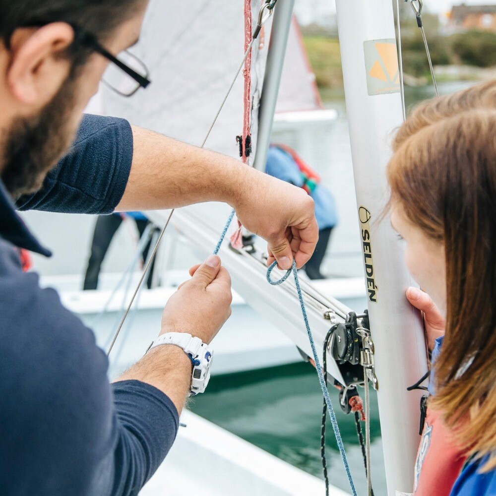 Instructor teaching girl knots to sail boat