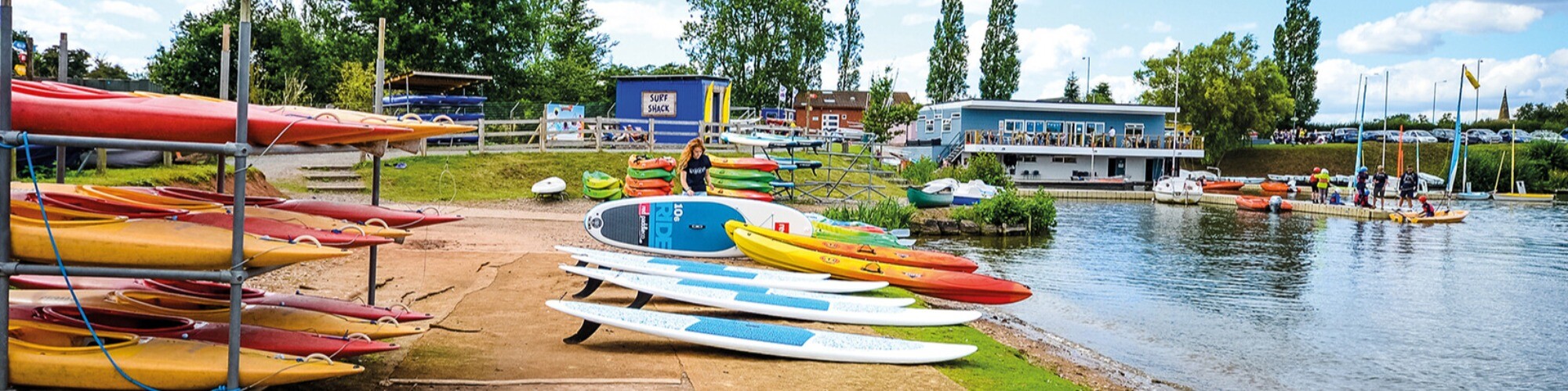 Woman organising single sit on top kayaks on beach