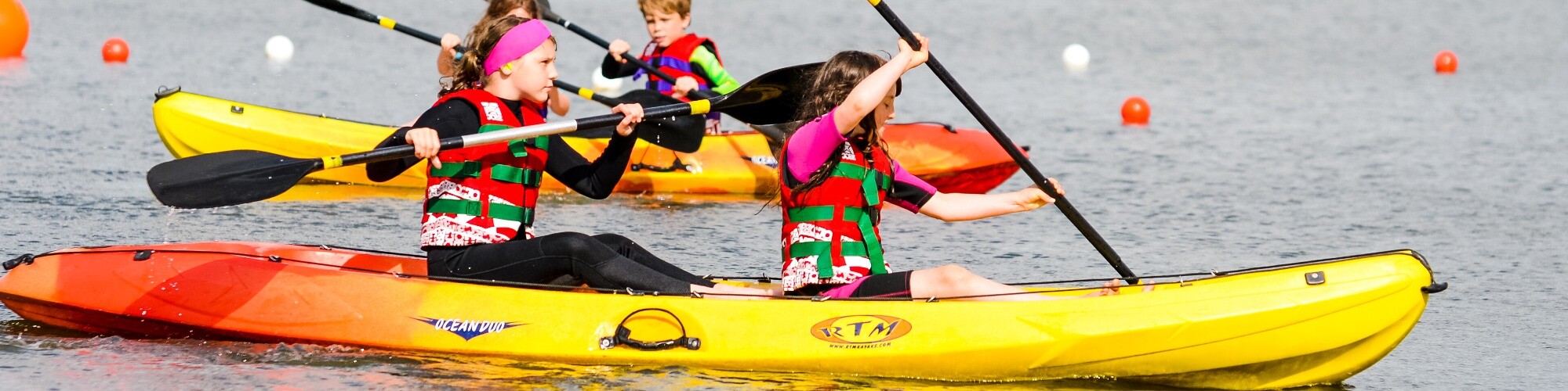 Four children in a double-sit-on-top hired Kayak on a body of water