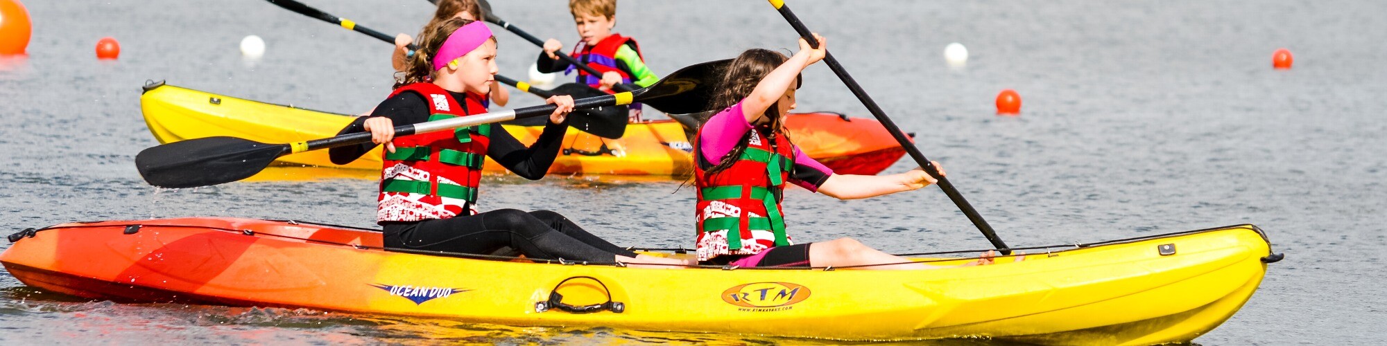 Four children in double kayaks on body of water